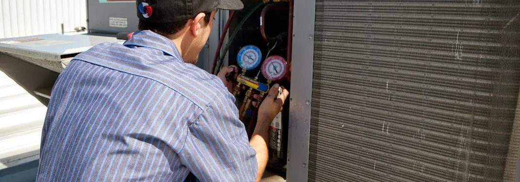 HVAC technician servicing a condenser unit in Paw Paw